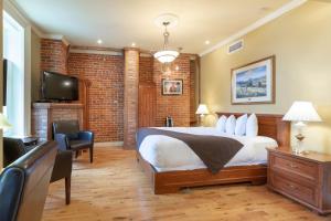 a bedroom with a bed and a tv and a brick wall at Unilofts Grande-Allée in Quebec City