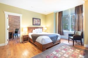 1 dormitorio con 1 cama, escritorio y sillas en Unilofts Grande-Allée en Quebec