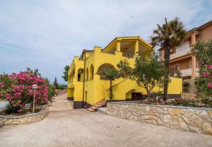 a yellow house with flowers in front of it at Apartment Vrbnik 2 in Vrbnik