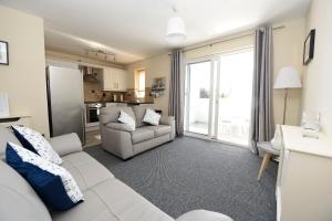 Una sala de estar con un sofá y una cocina. en Causeway Coast Apartments Kyla Marine, en Ballycastle