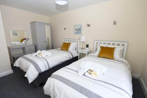 2 camas en una habitación de hotel con almohadas blancas y naranjas en Causeway Coast Apartments Kyla Marine, en Ballycastle