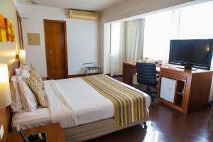 a hotel room with a bed and a desk and a television at Quality Porto Alegre in Porto Alegre