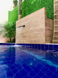 a swimming pool with a water fountain next to some palm trees at Del Rio Apart Hotel in Encarnación
