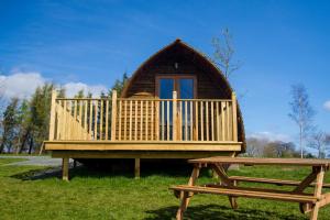 a large wooden cabin with a bench in front of it at Mains Farm in Stirling