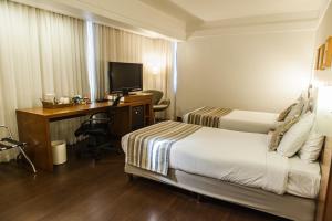 a hotel room with two beds and a desk with a computer at Quality Porto Alegre in Porto Alegre
