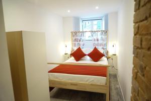 ein kleines Schlafzimmer mit einem Bett mit zwei roten Kissen in der Unterkunft Alfama Secret - Cozy&Sweet in Lissabon