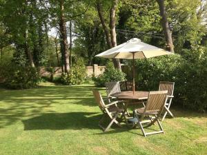 uma mesa e cadeiras com um guarda-sol num quintal em Tanglewood Gatwick Bed & Breakfast em Crawley