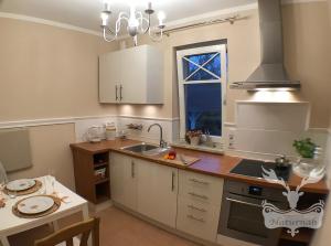 a kitchen with white cabinets and a sink and a window at Duft- und Parfümfreie Allergiker-FEWO in Mertendorf