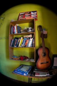a guitar sitting on a book shelf with books at Tilcara Hostel in Tilcara