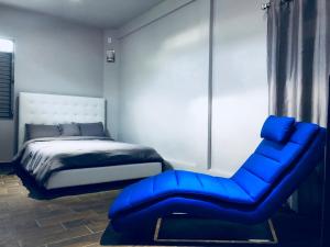 ein Schlafzimmer mit einem blauen Stuhl und einem Bett in der Unterkunft Modern Suite #0 - best location in Aguadilla