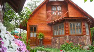 una pequeña casa de madera con flores delante en Cabanas Inti-Wari Jujuy en El Ceibal