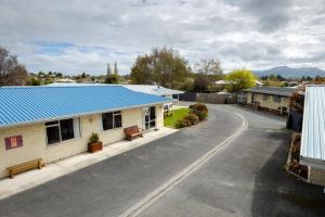 an empty street with a house with a blue roof at Esplanade Motels in Gore