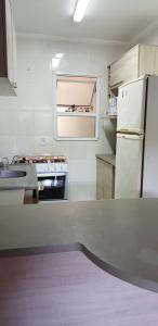 a kitchen with a white refrigerator and a sink at apartamento em bertioga in Bertioga