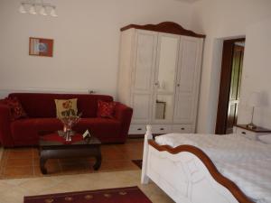 a living room with a bed and a red couch at Öreg Malom Hotel in Csepreg