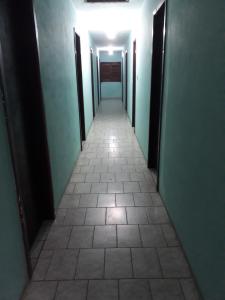 a corridor of a hallway with green walls and a tile floor at Pousada Minas Gerais in Tramandaí