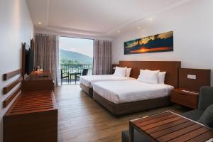 a hotel room with two beds and a balcony at The Bayview Beach Resort in Batu Ferringhi
