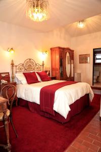 1 dormitorio con 1 cama grande y alfombra roja en El Hotel de Su Merced, en Sucre