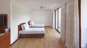 a white room with a bed and a window at The Bayview Beach Resort in Batu Ferringhi