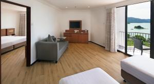 a hotel room with a bed and a couch and a television at The Bayview Beach Resort in Batu Ferringhi