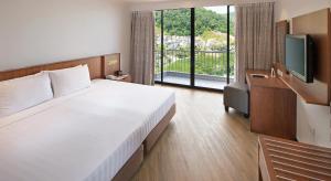 a hotel room with a bed and a television at The Bayview Beach Resort in Batu Ferringhi