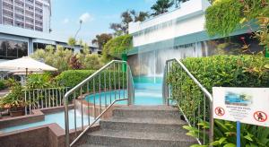 a staircase leading to a swimming pool with a waterfall at The Bayview Beach Resort in Batu Ferringhi