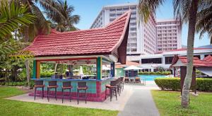 a bar with stools in a park with a building at The Bayview Beach Resort in Batu Ferringhi