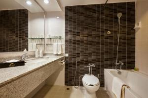 a bathroom with a toilet and a sink and a tub at The Bayview Beach Resort in Batu Ferringhi