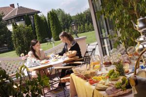 dos mujeres sentadas en mesas en un patio con comida en Öreg Malom Hotel, en Csepreg