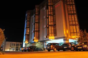 a building with cars parked in front of it at night at Hotel Emma Est in Craiova