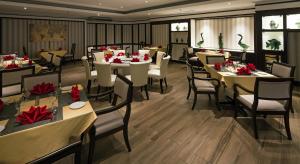a restaurant with tables and chairs with red flowers on them at The Bayview Beach Resort in Batu Ferringhi