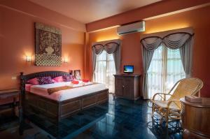 a bedroom with orange walls and a bed with pink pillows at Baan Georges Hotel in Sukhothai