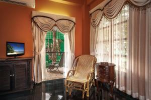 a living room with a chair and a window at Baan Georges Hotel in Sukhothai