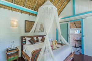 a bedroom with a bed with a mosquito net at Water Blow Huts in Nusa Lembongan