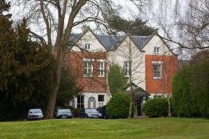 une grande maison avec des voitures garées devant elle dans l'établissement Coulsdon Manor Hotel and Golf Club, à Croydon