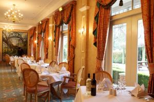 a dining room with tables and chairs and windows at Coulsdon Manor Hotel and Golf Club in Croydon