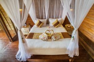 a bedroom with two beds with white drapes at Water Blow Huts in Nusa Lembongan