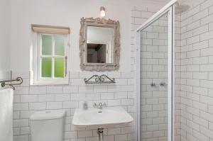 ein weißes Badezimmer mit einem Waschbecken und einem Spiegel in der Unterkunft Hotel Roosje van de Kaap in Swellendam