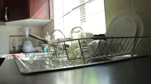 un portant rempli de vaisselle sur un comptoir de cuisine dans l'établissement Tap's Home Away from Home, à Gaborone