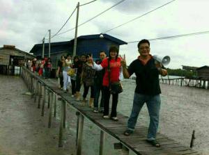 a group of people crossing a wooden bridge at Sea Lion Pulau Ketam Bungalow Homestay in Bagan Teochew