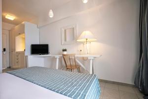 a bedroom with a bed and a desk with a television at Rigas Boutique Hotel & Spa in Afitos