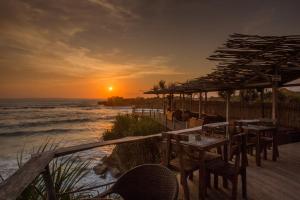 um pôr-do-sol na praia com mesas e cadeiras em Water Blow Huts em Nusa Lembongan