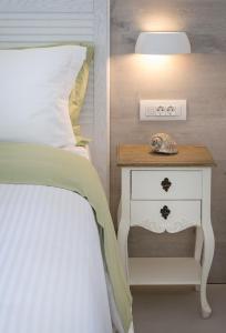 a bedroom with a bed and a nightstand with a lamp at White Pearls-Adults Only Luxury Suites in Kos