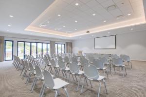 une salle de conférence avec des chaises et un écran de projection dans l'établissement Knysna Hollow Country Estate, à Knysna