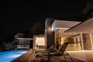 a villa with a swimming pool at night at Infinity Villa in Plomarion