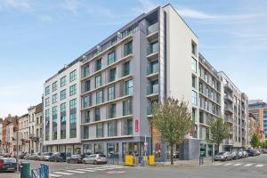 een hoog wit gebouw in een stadsstraat bij Appart'City Confort Bruxelles Centre Gare du Midi in Brussel