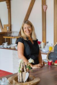 a woman standing at a counter with a vase at Pension Himmelreich in Glatt