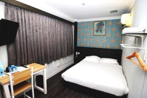 a small bedroom with a bed and a desk at HOTEL JJH Aliwal in Singapore