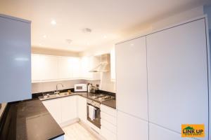 a kitchen with white cabinets and a black counter top at Holden Court Apartment - Apt 1 in West Drayton