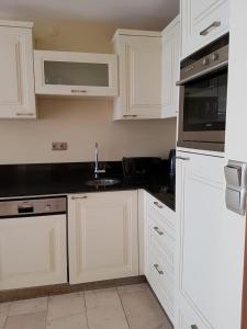 a white kitchen with white cabinets and a sink at Luxury Apartments in GoldCity Complex in Kargicak