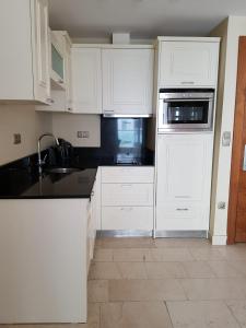 a kitchen with white cabinets and a sink and oven at Luxury Apartments in GoldCity Complex in Kargicak